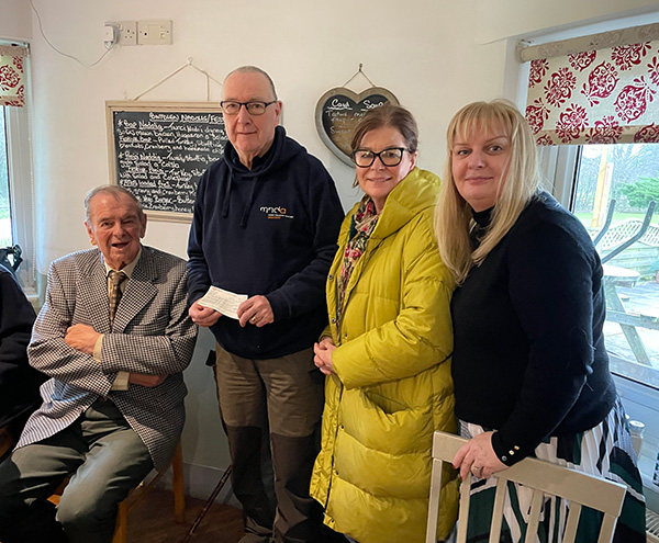 MND volunteer collecting a £150 check from Carmel Chapel